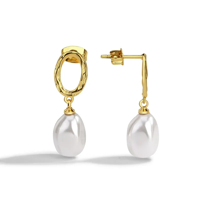 Boucles d’oreilles pendantes dorées pour femme, composées d’un ovale martelé doré et d’une perle blanche baroque suspendue. Bijou au style bohème chic et raffiné, lumineux et féminin, parfait pour sublimer une tenue naturelle ou romantique